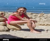 young girl in bathing suit sitting on lake beach with piles of rocks d6ng3y.jpg from teenbathing