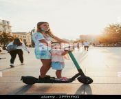 teenager girl and her sister preschooler riding an electric scooter in the city center concept of happy family candid people real moments authenti 2pfhfkg.jpg from real riding sister