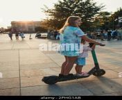 teenager girl and her sister preschooler riding an electric scooter in the city center concept of happy family candid people real moments authenti 2phg1ab.jpg from real riding sister
