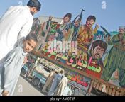 a pashto man and his child in front of a large cinema billboard featuring am6t5f.jpg from peshawar pasht