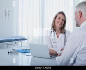 smiling female doctor talking to patient at desk in office eakjxr.jpg from trecky fake doctouer