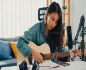 happy asia woman songwriter play acoustic guitar listen song from smartphone think and write notes lyrics song in paper sit in living room at home studio music production at home concept photo.jpg from 3655551 jpg