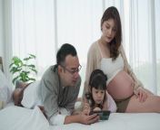 family including father pregnant mother and daughter using smartphone together in bedroom video.jpg from daugther pergenet with father video