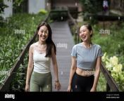 smiling fit asian girlfriends wearing tight casual clothes strolling along narrow wooden bridge in countryside and chatting 2ce85w2.jpg from asian girlfriend