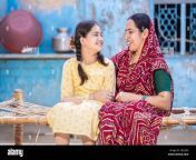 smiling young indian mother and adorable little daughter having a good time togethersitting on traditional bed cute child girl in braided hair and m 2gcj562.jpg from indian mother m