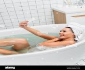 young woman in towel taking selfie on smartphone and sticking out tongue in bath 2dhbcam.jpg from bath selfi