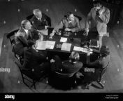1930s six men and one woman sitting around office desk while one man aamx5h.jpg from tel and woman six