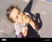 la pequena nina con cara sucia disfruta chupando el helado de chocolate de la parte inferior del cono en las calles de la ciudad 2aje028.jpg from pequeña niña de escuela desnuda
